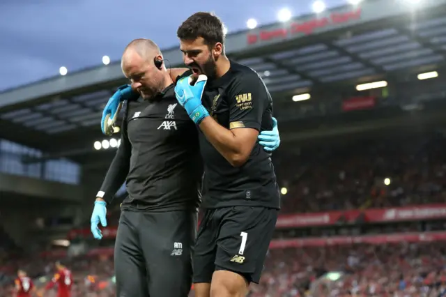 Alisson is helped off the pitch