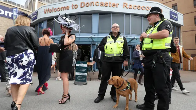 Police and sniffer dogs stand at the entrance to Doncaster Racecourse