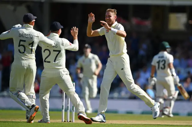 Stuart Broad (C) celebrates with teammates after taking the wicket of Australia's Steve Smith during play on the fourth day of the fifth Ashes cricket Test match between England and Australia at The Oval