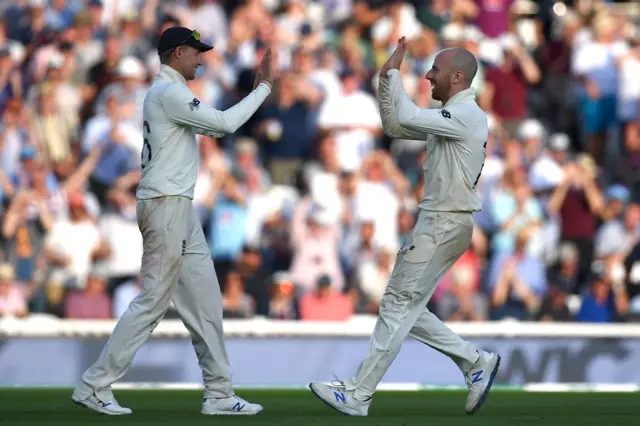 England's captain Joe Root (L) celebrates with England's Jack Leach (R) after taking the wicket of Australia"s Matthew Wade during play on the fourth day of the fifth Ashes cricket Test match between England and Australia at The Oval