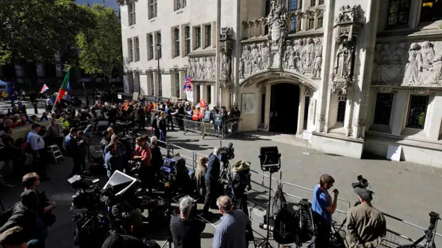 Members of the media stand opposite the entrance to the Supreme Court in central London, on the first day of the hearing into the decision by the government to prorogue parliament