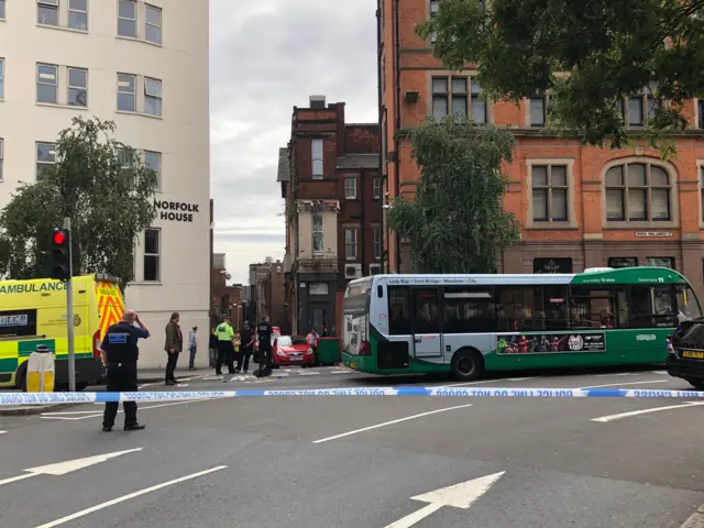 A bus and ambulance behind the cordon