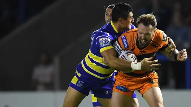 Jordan Rankin of Castleford Tigers is tackled by Bryson Goodwin of Warrington Wolves