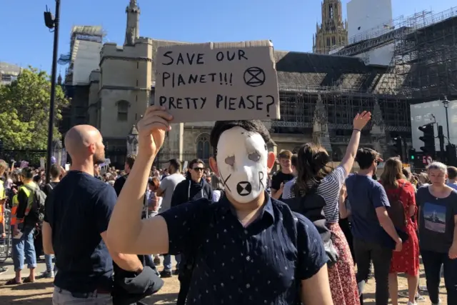 Protester in London holding a sign that says: "Save our planet!!! Pretty please?"