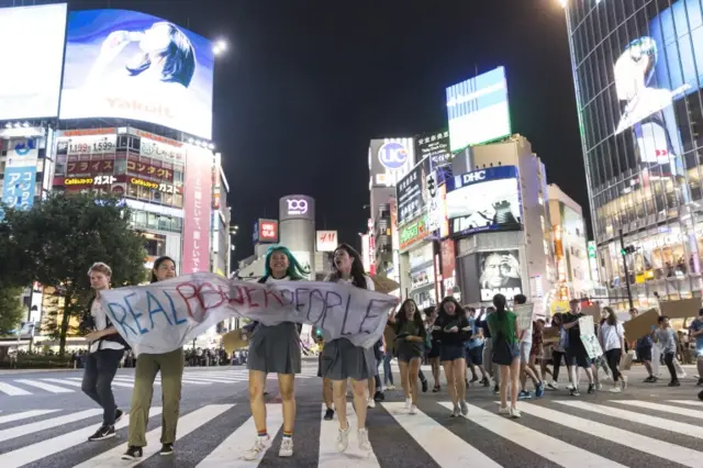 Climate protesters next to neon lights in Tokyo