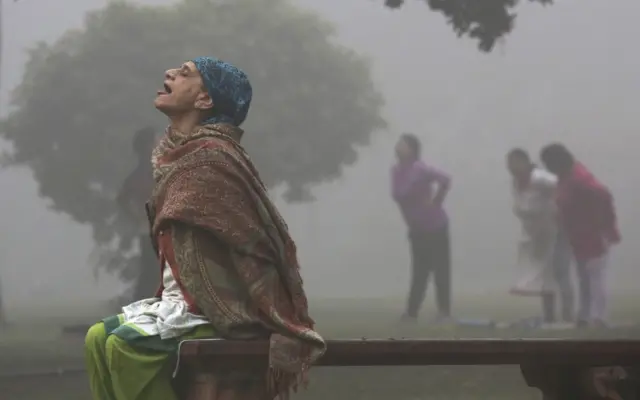 An Indian woman performs yoga as the Lodhi garden is engulfed in heavy smog