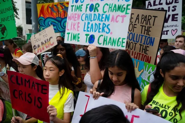 Young demonstrators carry colourful placards