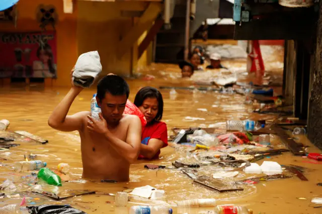 People wade through dirty floodwater and rubbish in Jakarta, Indonesian in 2018