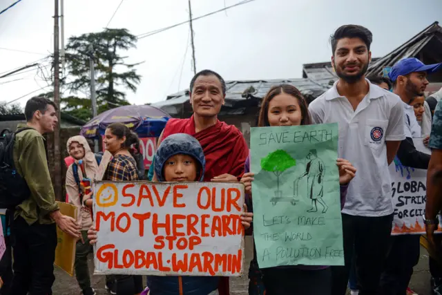 Two children and a monk hold placards for the protest