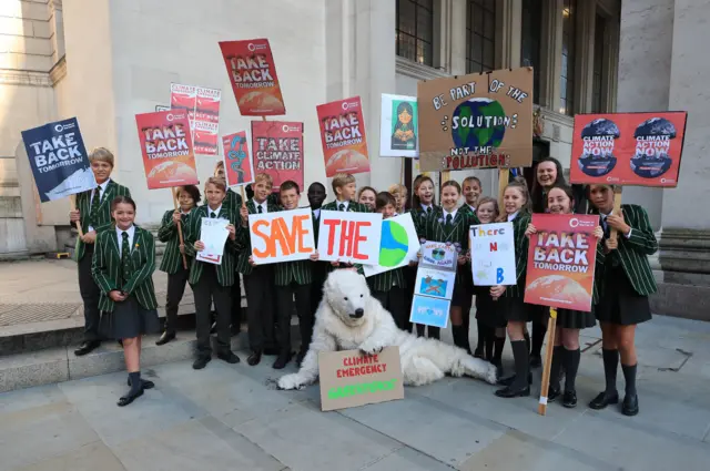 Children with placards and a person in a polar bear suit