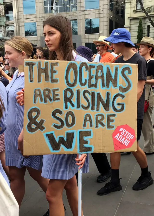 A student protester holds a placard in Melbourne saying: "The oceans are rising and so are we."