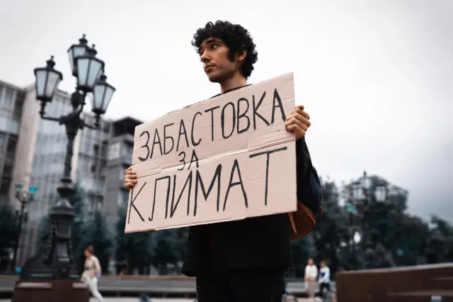 Arshak Makichyan with sign in Russian saying "Strike for Climate"