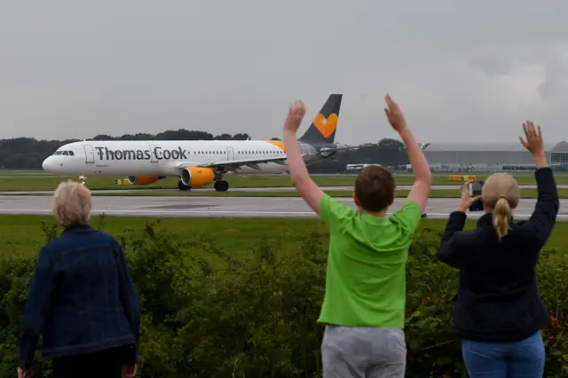 People waving at Thomas Cook plane