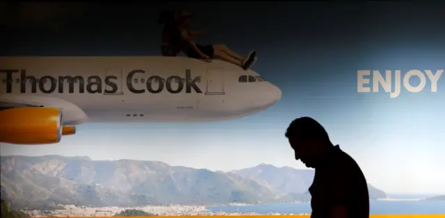 Man stands in front of Thomas Cook advert at Dalaman airport