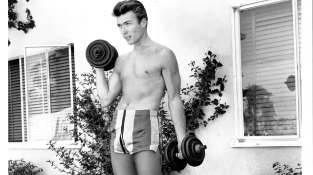 Actor Clint Eastwood works out with dumbbells at home on June 1, 1956 in Los Angeles, California