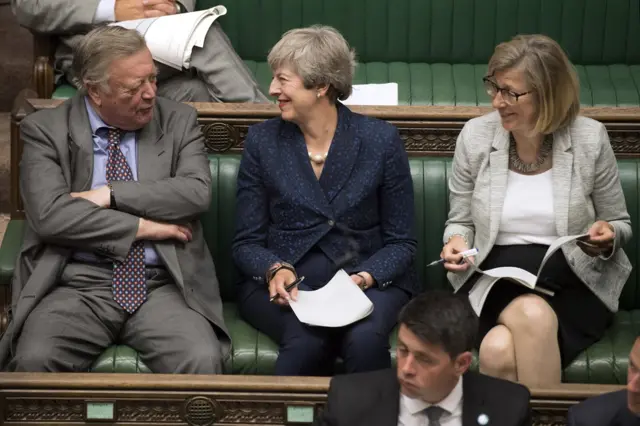 Boris Johnson's predecessor Theresa May smiles at the Father of the House of Commons Ken Clarke, as she makes herself comfortable in the backbenches