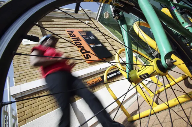 Halfords sign seen through the spokes of a bike wheel