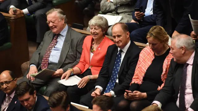 Former PM Theresa May smiles from the backbenches