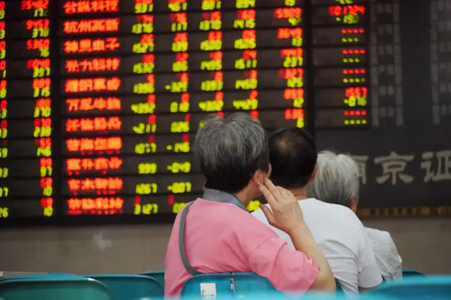 Investors watch an electronic ticker board displaying stock figures at a stock market on August 29, 2019 in Nanjing, Jiangsu Province of China