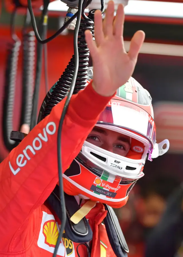 Charles Leclerc waves to fans in the paddock