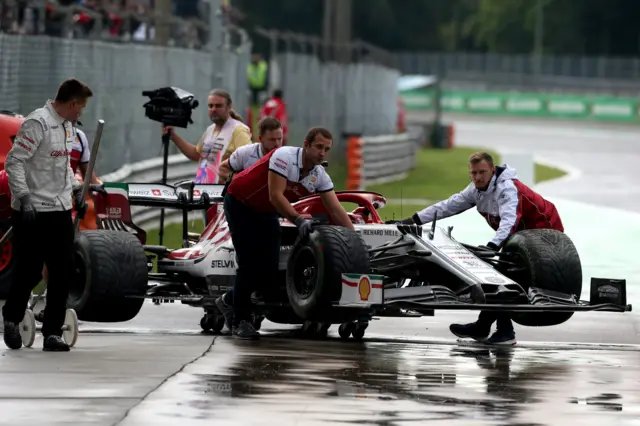 Kimi Raikkonen's car is pushed back into the pits