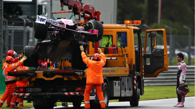 Sergio Perez watches as his Racing Point car is towed away