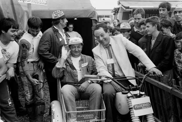 French humorist Coluche poses in the side-car of a motorcycle after giving the start of the 24 Hours motorcyclists of Brittany in Ploubalay on 31 August, 1985