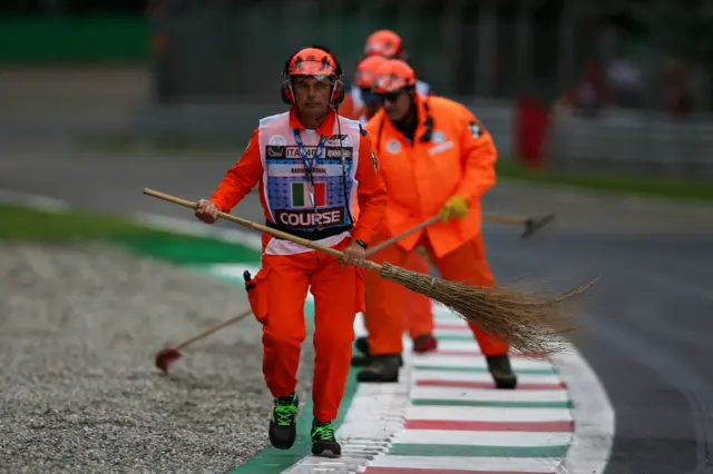 Marshals sweep gravel from the track