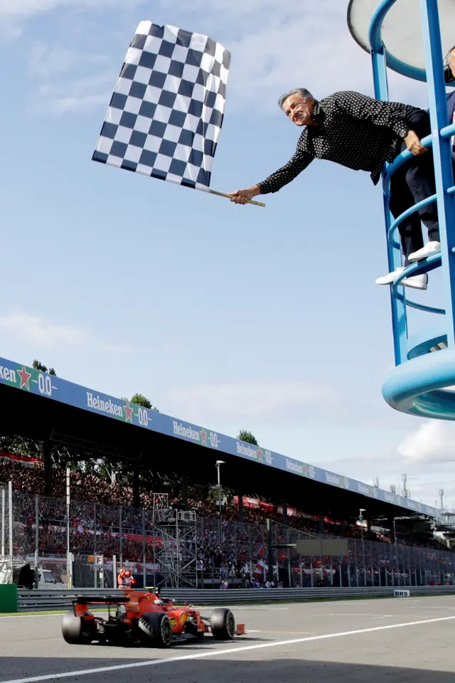 Jean Alesi waves the chequered flag as Charles Leclerc wins