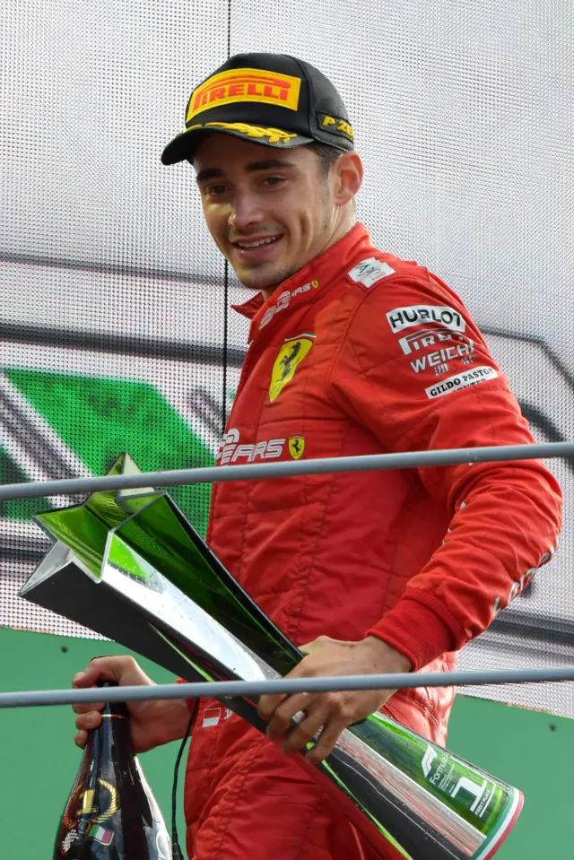 Charles Leclerc leaves the podium with trophy and champagne bottle