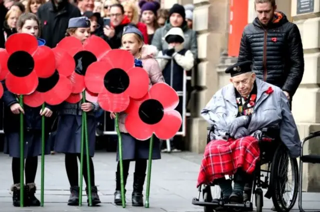 Children holding giant poppies joined a war veteran during the Remembrance Day service at the Stone of Remembrance in Edinburgh