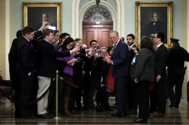 Senate Minority Leader Chuck Schumer speaks to journalists who are forced to work under a different set of restrictions during the impeachment trial