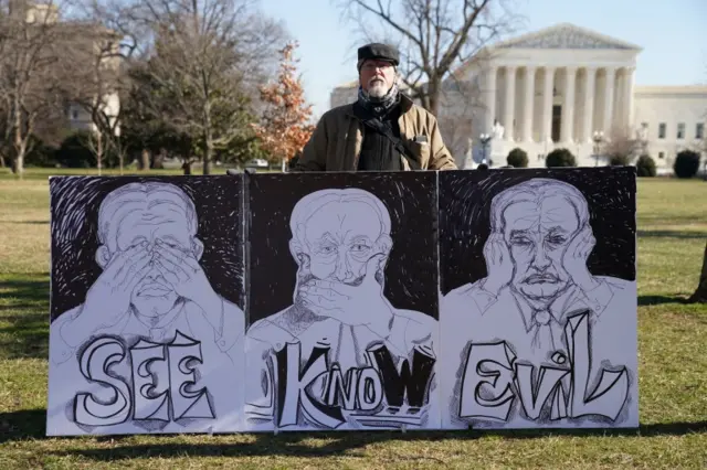 A protester holds a sign on Capitol Hill with the Supreme Court in the background