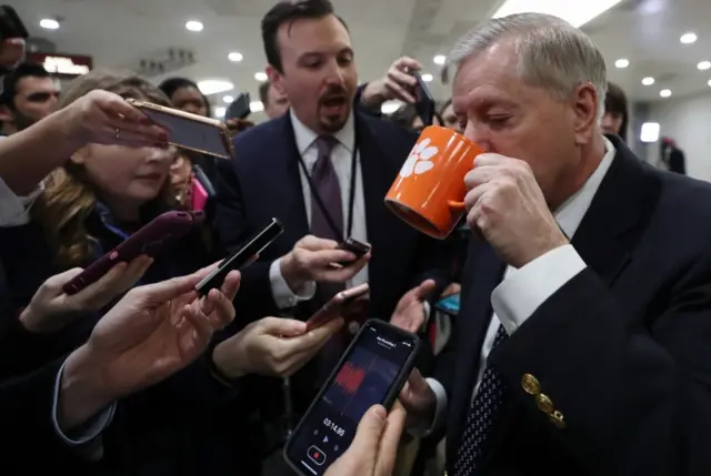 Sen. Lindsey Graham (R-SC) takes a sip from his coffee mug as he speaks to reporter