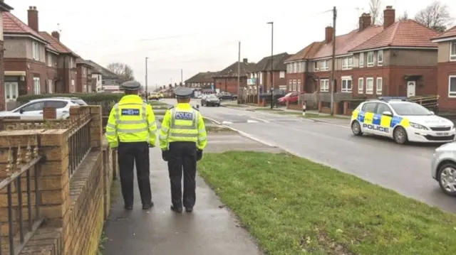 Two officers walk on a road