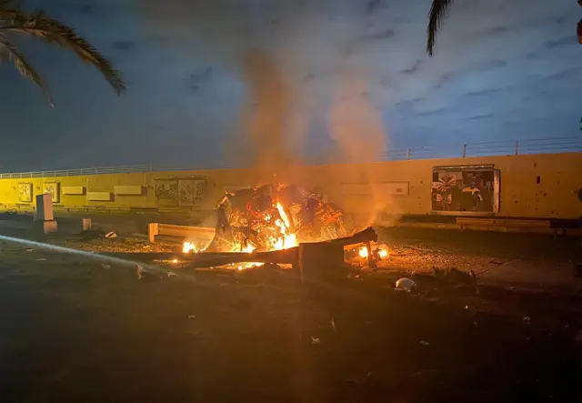 A picture published by the media office of the Iraqi military's joint operations forces shows a destroyed vehicle on fire following the US strike on 3 January, 2020.