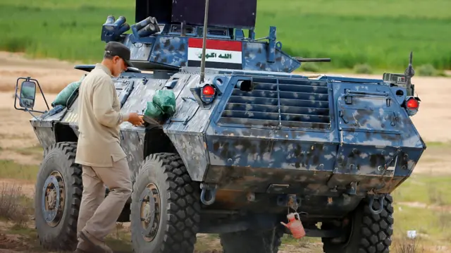 Soleimani walks near an armoured vehicle at the frontline during offensive operations against Islamic State militants in the town of Tal Ksaiba in Salahuddin province March 8, 2015