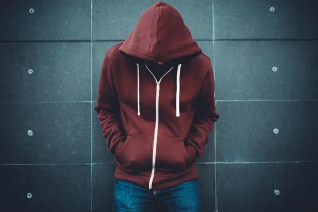 Teenager standing next to a wall