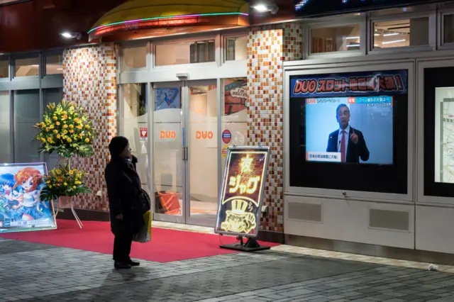 Someone in Japanese watching Carlos Ghosn news conference on screen