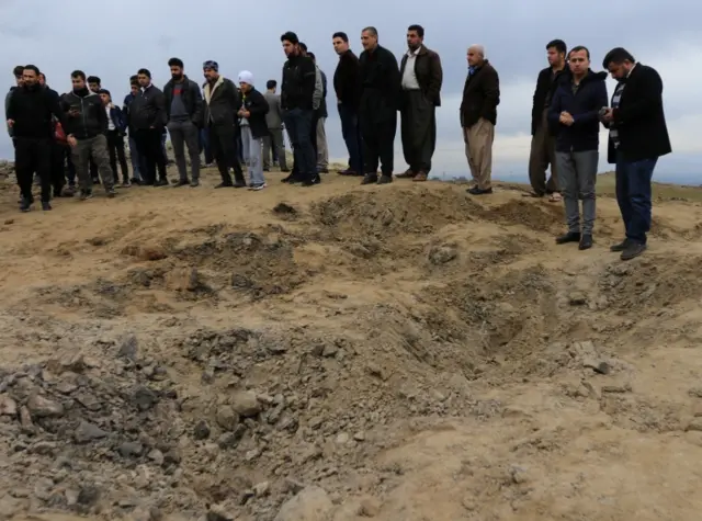 People inspect what they believe is a crater caused by an Iranian missile, near Dohuk, Iraq