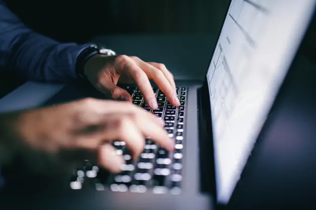 Hands typing on a laptop