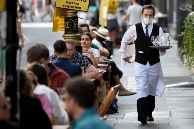 A waiter serving outside tables at a bar