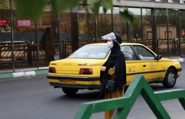 People wear masks as a precaution against the novel coronavirus (Covid-19) pandemic as they go out in Tehran, Iran