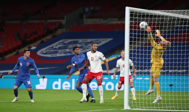 Denmark's goalkeeper Kasper Schmeichel (R) dives to save a header from England's midfielder Mason Mount