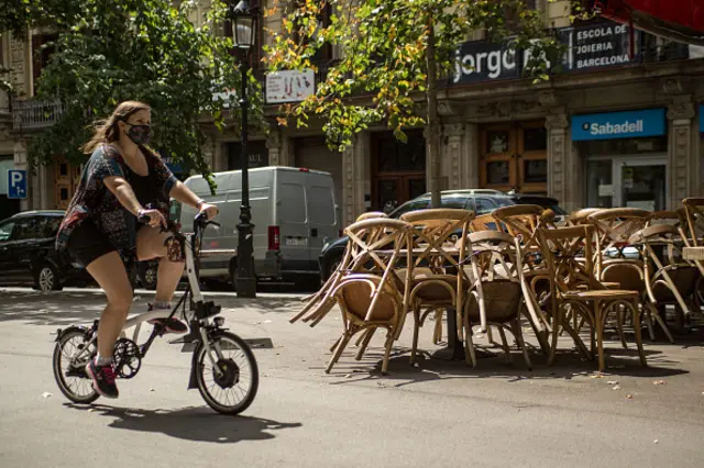 A woman wearing a face mask rides past an empty restaurant. Barcelona extends the restrictions due to Covid-19 for another 15 days, where it has extended the 50% limitation of the capacity of bars, restaurants and terraces