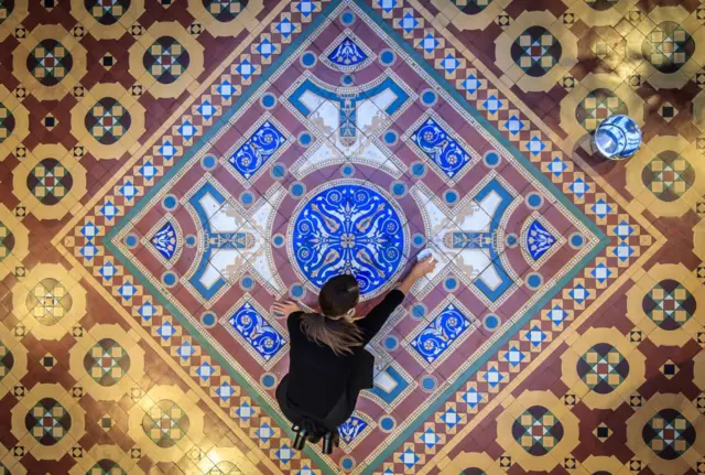 Bar Convent employee Lauren Masterman cleans a historic George and Arthur Maw tiled floor.