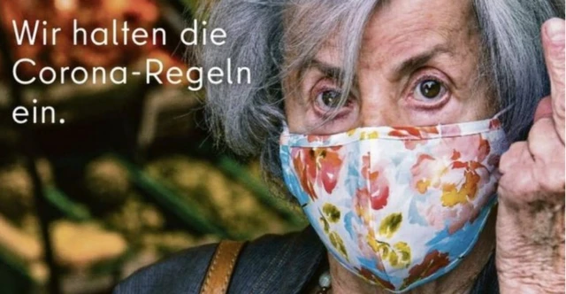 A poster in Germany shows an elderly woman giving the middle finger to people who refuse to wear masks