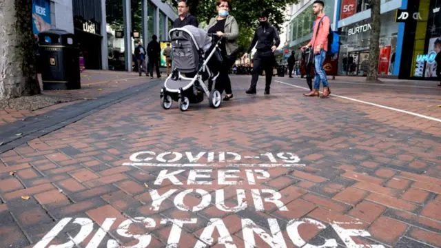 A sign on a street telling people to keep their distance