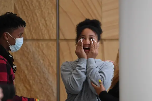 A passenger reacts as she arrives from New Zealand, at Sydney International Airport in Sydney, Australia, on 16 October 2020