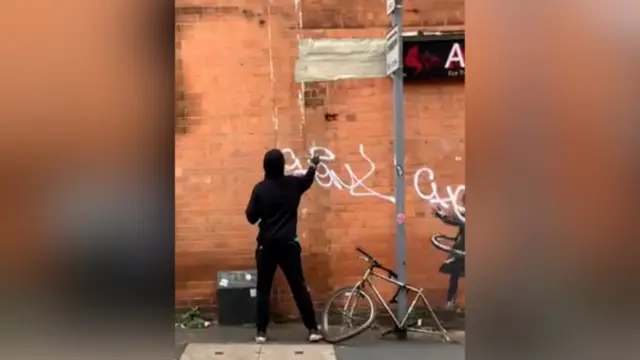 Man spray painting over Nottingham Banksy-style artwork